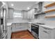 Well-lit kitchen featuring grey cabinets, stainless steel appliances, and hardwood flooring at 7 Georgia Ave, Crystal Beach, FL 34681
