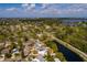 An aerial view captures a home nestled near a pond in a neighborhood with clear skies and distant water views at 8001 Orient Ne Way, St Petersburg, FL 33702
