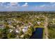 An aerial view displays a home near a serene pond in a neighborhood surrounded by lush greenery and clear blue skies at 8001 Orient Ne Way, St Petersburg, FL 33702