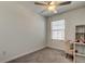 Bright bedroom featuring a ceiling fan, gray carpet, a cozy chair, and a small desk for a functional space at 8294 Corner Pine Way, New Port Richey, FL 34655