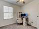 A well lit bedroom is furnished with gray carpet, a ceiling fan, and a desk with computer monitors at 8294 Corner Pine Way, New Port Richey, FL 34655