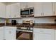 Modern kitchen featuring stainless steel appliances, white cabinets, and granite countertops at 8294 Corner Pine Way, New Port Richey, FL 34655