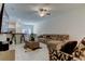 Bright living room featuring neutral tile flooring, a ceiling fan, and open access to the kitchen at 8294 Corner Pine Way, New Port Richey, FL 34655