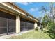 Back exterior view of home with enclosed patios, green grass, and landscaping at 8421 Pine River Rd, Tampa, FL 33637