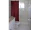 Clean bathroom showcasing a white vanity, toilet, and a shower/tub combination with white tile and red curtains at 8525 111Th St # 210, Seminole, FL 33772