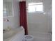 Clean bathroom showcasing a white vanity, toilet, and a shower/tub combination with white tile and red curtains at 8525 111Th St # 210, Seminole, FL 33772