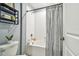 Clean bathroom with white subway tile and shower curtain, next to a toilet and shelving unit at 8887 Little Bluestem Dr, Land O Lakes, FL 34637