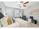 Bright bedroom with a ceiling fan, queen size bed, sitting chair, and natural light through the windows at 8887 Little Bluestem Dr, Land O Lakes, FL 34637