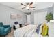 Bright bedroom with a ceiling fan, queen size bed, sitting chair, closet, and natural light through the windows at 8887 Little Bluestem Dr, Land O Lakes, FL 34637