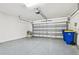 Garage featuring sealed concrete floors, garage door and two blue waste bins at 8887 Little Bluestem Dr, Land O Lakes, FL 34637