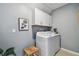Well-lit laundry room with gray walls, white cabinets, washer, dryer, and a decorative plant at 8887 Little Bluestem Dr, Land O Lakes, FL 34637
