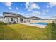 Backyard view of pool and hot tub with stone tile surround and grassy yard at 8887 Little Bluestem Dr, Land O Lakes, FL 34637