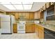 Functional kitchen with white appliances, oak cabinets, and a neutral backsplash at 9 Haig Pl # 310, Dunedin, FL 34698