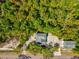 Aerial view of a house and detached structure surrounded by verdant landscaping, trees, and expansive driveway at 920 E Lake Dr, Tarpon Springs, FL 34688