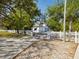 Two-story home entrance with white picket fence, stone driveway, and tree-lined surroundings at 920 E Lake Dr, Tarpon Springs, FL 34688