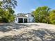 Spacious garage with multiple bays, open doors, and ample parking on concrete pad surrounded by mature trees at 920 E Lake Dr, Tarpon Springs, FL 34688