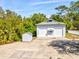 Large two-car garage with a matching storage shed sits on a concrete pad surrounded by mature trees at 920 E Lake Dr, Tarpon Springs, FL 34688