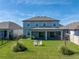 Well-maintained backyard featuring a covered patio, lush green lawn, and inviting Adirondack chairs at 11232 Bram Bay Ct, San Antonio, FL 33576