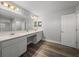 Bright bathroom with double vanity, a large mirror, and wood look flooring at 11232 Bram Bay Ct, San Antonio, FL 33576