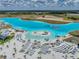 Aerial view of a resort-style community pool with sandy beach, tiki huts, and crystal-clear turquoise water at 11232 Bram Bay Ct, San Antonio, FL 33576