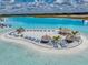 Stunning aerial view of a community pool featuring tiki huts and lounge chairs on a pristine sandy beach at 11232 Bram Bay Ct, San Antonio, FL 33576