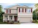 Charming two-story home featuring a covered porch, two-car garage, and red window shutters at 12055 Kingsley Trl, Parrish, FL 34219