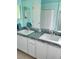 Bathroom featuring a double sink vanity with tiled countertop, framed mirror, and bright lighting at 1318 Misty Greens Dr, Sun City Center, FL 33573
