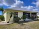 Rear exterior of home featuring a screened lanai, a yellow facade, and manicured landscaping at 1318 Misty Greens Dr, Sun City Center, FL 33573