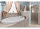 This bathroom features a soaking tub with tile surround, a glass shower, and a window with curtains at 13424 Hunters Point St, Spring Hill, FL 34609