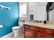 Bright bathroom featuring blue accent wall, single sink vanity and a standard toilet with window at 13424 Hunters Point St, Spring Hill, FL 34609