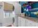 Laundry room with stacked washer/dryer, white cabinets, granite countertops, and blue accent wall at 13424 Hunters Point St, Spring Hill, FL 34609