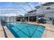 Screened-in pool with spa, lounge chairs, dining, and an outdoor ceiling fan at 13424 Hunters Point St, Spring Hill, FL 34609