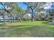Expansive green backyard with mature trees, offering ample space and scenic views of the surrounding lake at 13908 Paradise Ln, Dade City, FL 33525