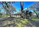 Exterior view of the home showcasing the well-maintained yard and natural surroundings with mature trees and lush grass at 13908 Paradise Ln, Dade City, FL 33525