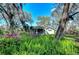 Charming exterior view, framed by lush greenery with vibrant flowers and mature trees, creating a peaceful setting at 13908 Paradise Ln, Dade City, FL 33525
