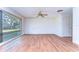 Spacious living room featuring hardwood floors, a ceiling fan, and a big window showcasing a large tree at 13908 Paradise Ln, Dade City, FL 33525