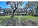 Sprawling lawn and landscaping surround the home, embraced by majestic oak trees at 13908 Paradise Ln, Dade City, FL 33525