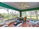 Relaxing screened porch with outdoor furniture, view of the verdant backyard, and hanging fan at 13908 Paradise Ln, Dade City, FL 33525