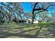 Lush yard with mature trees and lake in the background at 13908 Paradise Ln, Dade City, FL 33525