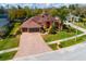 Lovely aerial view of a terracotta colored house showing the well maintained lawn and beautiful brick driveway at 17104 Tiffany Lake Pl, Lutz, FL 33549