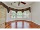 Bedroom featuring hardwood floors, ceiling fan, and multiple windows dressed with decorative curtains at 17104 Tiffany Lake Pl, Lutz, FL 33549