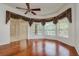 Bedroom featuring hardwood floors, a ceiling fan, multiple windows dressed with decorative curtains and roller shades at 17104 Tiffany Lake Pl, Lutz, FL 33549