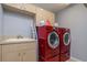 Functional laundry room featuring a sink, countertop, and red front-load washer and dryer at 17104 Tiffany Lake Pl, Lutz, FL 33549