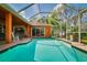 Sparkling screened-in pool boasts serene views of the green lawn, mature trees, and blue skies at 17104 Tiffany Lake Pl, Lutz, FL 33549