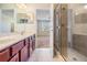 Bright bathroom featuring a double sink vanity, open doorway to a bedroom, and a tiled glass shower at 26932 Juniper Bay Dr, Wesley Chapel, FL 33544