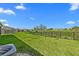 View of well maintained backyard with healthy green grass and a view of the neighborhood beyond the black metal fence at 3528 Golden Wheat Ln, Plant City, FL 33565