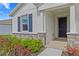 Welcoming front porch featuring stone accents, a blue door, and landscaped garden beds at 3528 Golden Wheat Ln, Plant City, FL 33565