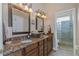 Double vanity bathroom features granite countertops, framed mirrors, and ample lighting fixtures at 3668 Janus Way, Palm Harbor, FL 34685