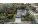 A landscaped property featuring a three-car garage and mature trees at 3668 Janus Way, Palm Harbor, FL 34685