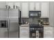 Modern kitchen with stainless steel appliances, mosaic backsplash, and white cabinets at 3668 Janus Way, Palm Harbor, FL 34685